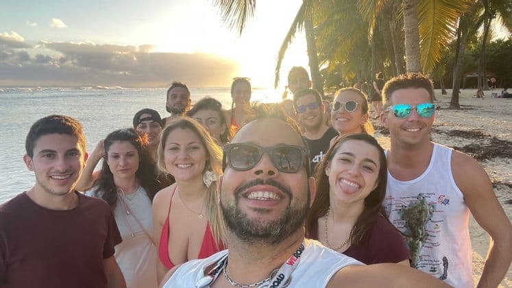 Eine WeRoad-Gruppe macht ein Selfie an einem tropischen Strand bei Sonnenuntergang.