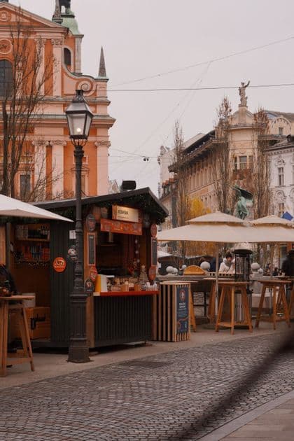 An outdoor market stall on a cobblestone street in a city square with historic buildings in the background.