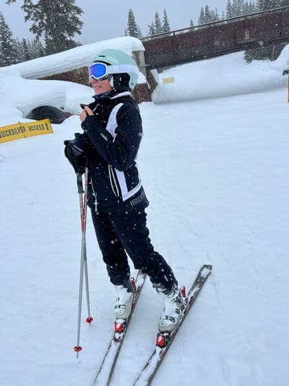 Un sciatore con casco, occhiali e tuta invernale si trova sulle piste innevate mentre nevica.