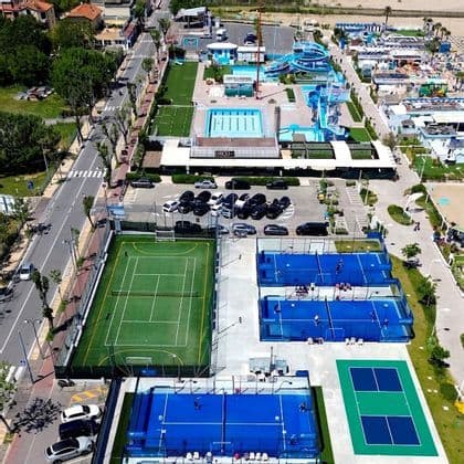 Vista dall'alto di un complesso sportivo all'aperto con campi da padel, un campo da tennis, una piscina e scivoli d'acqua