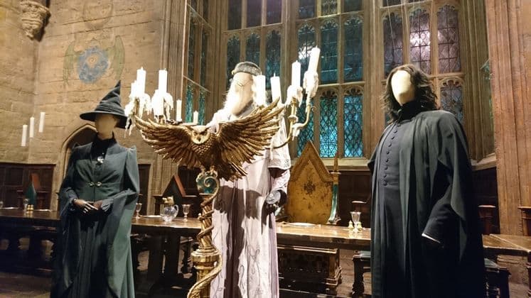 Una mostra di costumi per i personaggi Dumbledore, McGonagall e Snape su manichini in un set cinematografico di una grande sala.