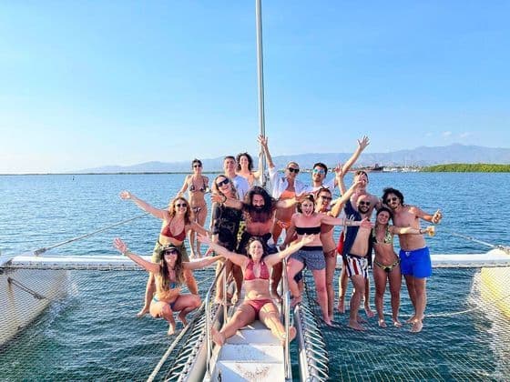 Eine WeRoad Gruppenreise posiert gemeinsam auf dem Netz eines Katamarans auf dem Meer an einem sonnigen Tag.