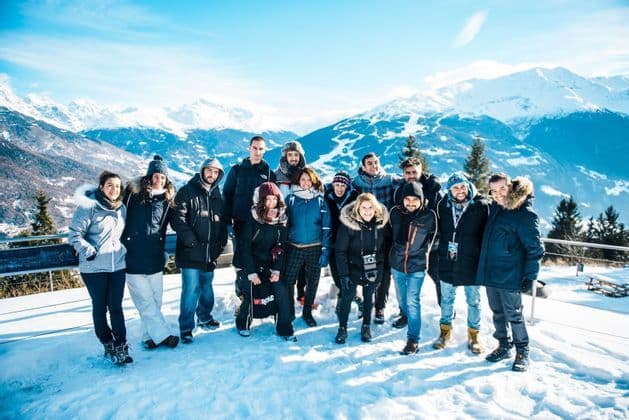Eine WeRoad-Gruppenreise posiert für ein Foto auf einem verschneiten Berg mit Panoramablick auf weitere Gipfel.