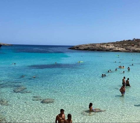 Un viaggio di gruppo WeRoad, tra nuoto e relax nelle limpide acque turchesi di una caletta rocciosa, sotto un cielo azzurro.