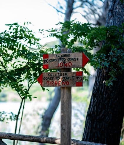 Un segnavia in legno con frecce rosse per il percorso Kalabria Coast to Coast, che indica Jonio e Tirreno.