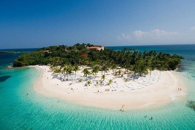 Una vista aérea de una península de isla tropical con una playa de arena blanca, agua turquesa y palmeras.