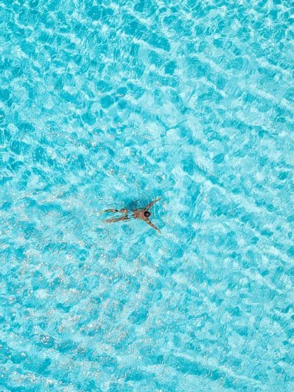 Vista aerea di una persona che galleggia sulla schiena in acque turchesi scintillanti
