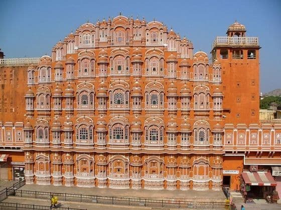 La intrincada fachada de varios niveles de un palacio de color terracota con numerosas pequeñas ventanas arqueadas bajo un cielo azul.