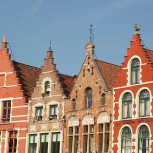 Una fila di colorati edifici in mattoni con distintive facciate a gradoni si staglia contro un cielo azzurro limpido.