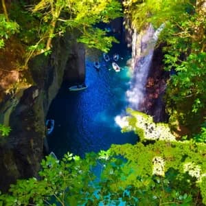 Veduta aerea di un viaggio di gruppo WeRoad che pagaia in barca in una gola stretta con acqua blu vibrante e una cascata.