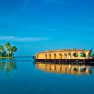 Ein traditionelles Holzhausboot mit Reetdach schwimmt auf ruhigem blauem Wasser, mit Palmen an einem fernen Ufer.
