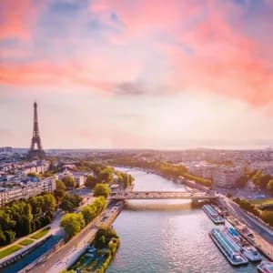Una vista aerea dello skyline di Parigi con la Torre Eiffel e il fiume Senna sotto un tramonto drammatico rosa e arancione.