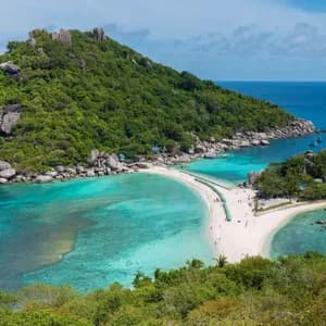 Vista aérea de un banco de arena blanco que conecta dos islas rocosas, verdes y exuberantes en aguas claras de color turquesa.