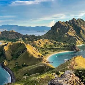 Una vista panoramica da una collina su isole verdi ondulate, baie turchesi e spiagge di sabbia bianca sotto un cielo nuvoloso.