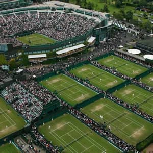 Aerial view of a large tennis complex with a main stadium and multiple courts packed with spectators during a tournament.