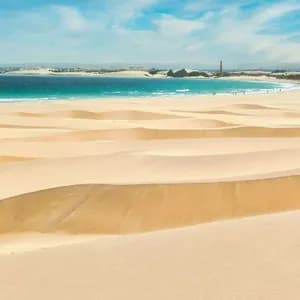 Un viaggio di gruppo WeRoad tra ampie dune di sabbia, affacciate su un oceano turchese sotto un cielo parzialmente nuvoloso.