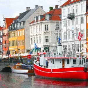 A bright red boat is moored in a canal alongside a waterfront lined with colorful, multi-story historic buildings.