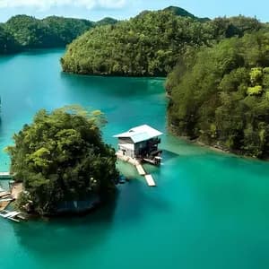Una moderna casa su palafitte sorge su una piccola isola in un fiume turchese, circondata da lussureggianti colline ricoperte di giungla.