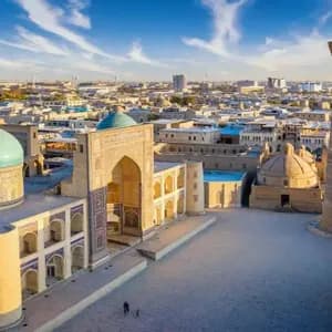 Vista aérea de una plaza histórica con una cúpula turquesa y un minarete alto al amanecer.