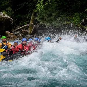 Un viaggio di gruppo WeRoad, indossando caschi e giubbotti di salvataggio, fa rafting in acque bianche turbolente, pagaiando tra grandi spruzzi.