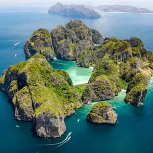 An aerial view of a green, rocky archipelago in a calm blue sea, with small boats sailing around its base.