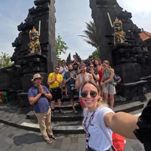 Un gruppo WeRoad posa per un selfie con una guida, facendo un gesto di preghiera davanti a un tradizionale portale in pietra nera.