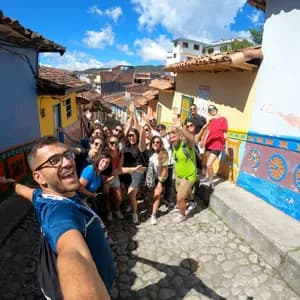 Un groupe WeRoad prend un selfie souriant dans une rue pavée étroite entre des bâtiments colorés.