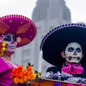 Due persone in costumi tradizionali e sombreri con i volti dipinti come teschi calavera per una festa.