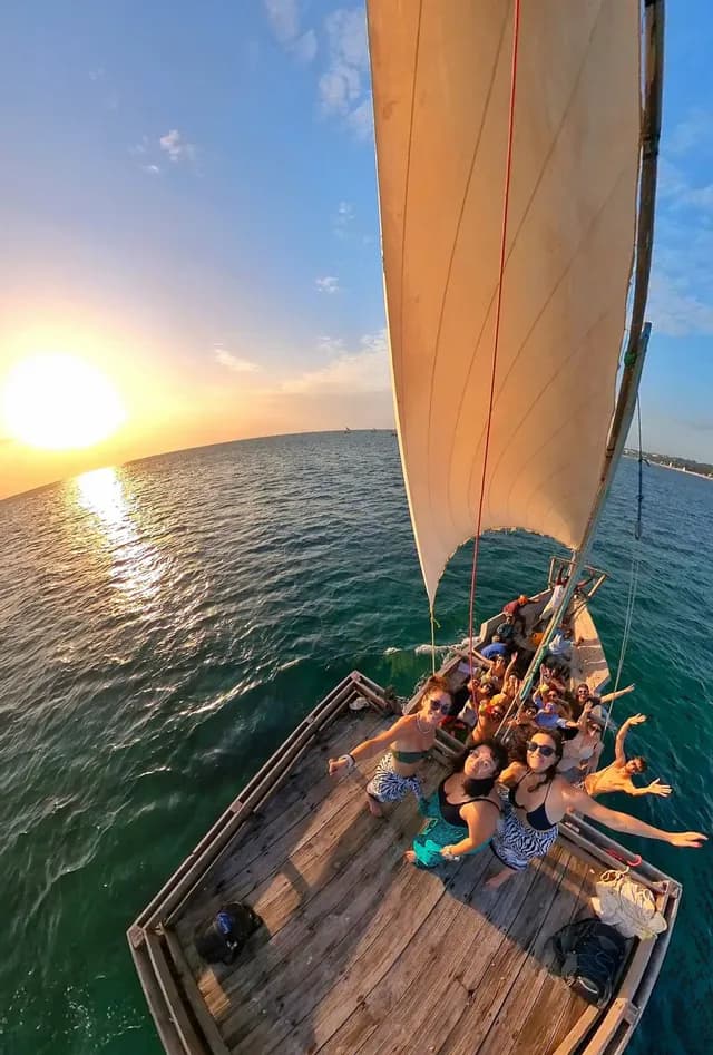 WeRoad-Gruppenreise auf einem Holzsegelboot: Teilnehmer posieren und lächeln beim Sonnenuntergang über dem Meer.