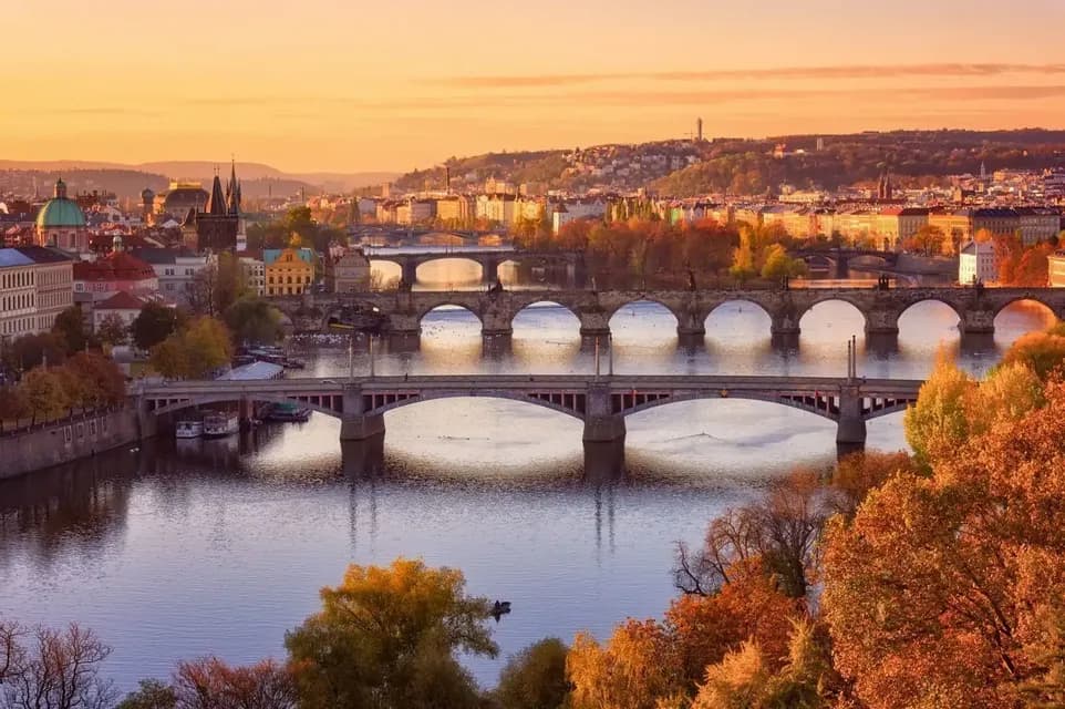 Une vue aérienne de plusieurs ponts traversant une rivière à travers une ville avec un feuillage d'automne au coucher du soleil.