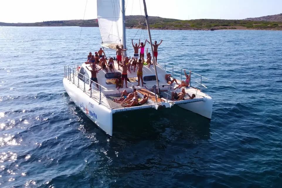 Un viaje en grupo de WeRoad con gente de fiesta y tomando el sol en un gran catamarán en mar abierto.