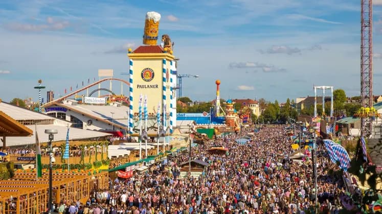 Una veduta aerea di una folla immensa che riempie le strade di un festival all'aperto con grandi tende e giostre.