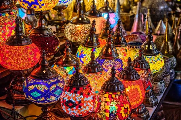 Une collection de lampes mosaïques colorées et illuminées, aux motifs complexes, exposées sur une table.