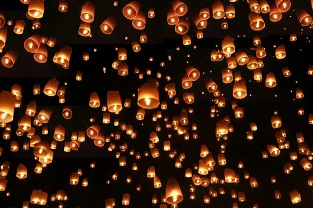 Una moltitudine di lanterne di carta luminose che fluttuano verso l'alto in un cielo notturno scuro.