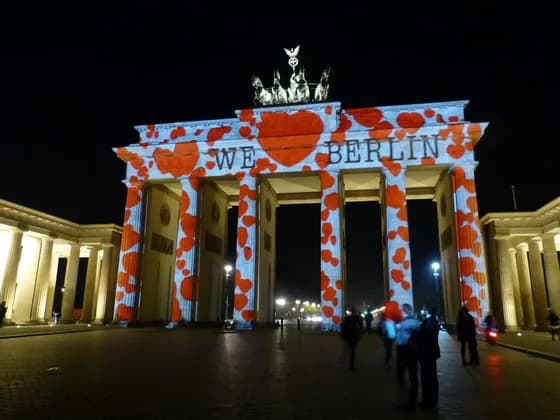 La Porta di Brandeburgo di notte, illuminata con una proiezione di cuori rossi e la scritta 'WE LOVE BERLIN'.