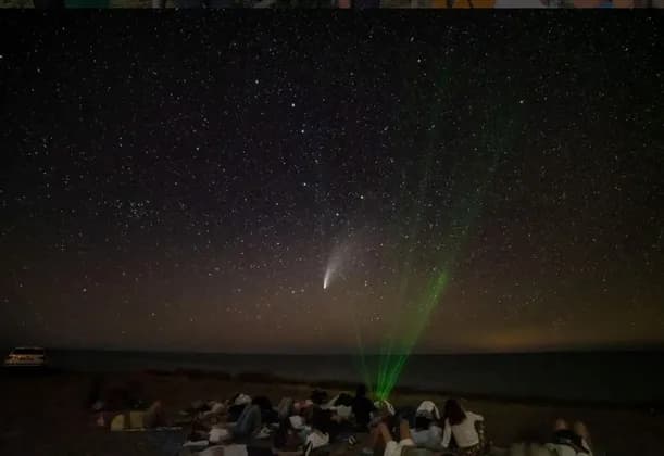 Un viaggio di gruppo WeRoad per osservare le stelle e una cometa su una spiaggia di notte, sotto un cielo stellato.
