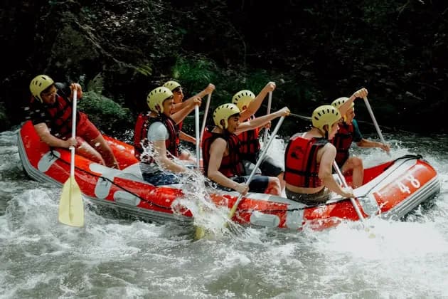 Un gruppo WeRoad rema all'unisono in un gommone rosso lungo un fiume di rapide.