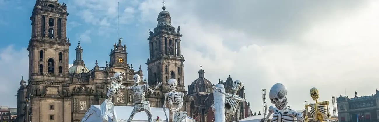 Grandes figuras de esqueletos para el festival del Día de Muertos están en exhibición frente a una catedral histórica.