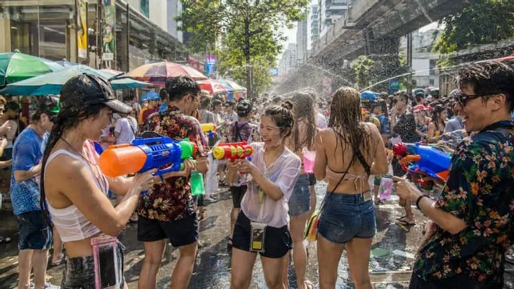 Un viaggio di gruppo WeRoad con persone che ridono e si spruzzano con pistole ad acqua in una via affollata di città.