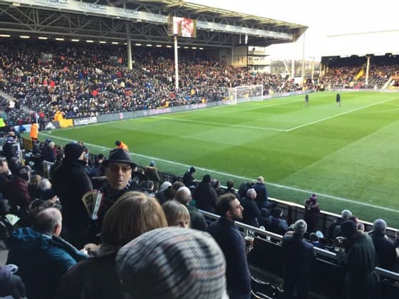 Gli spettatori riempiono le tribune di uno stadio di calcio che si affaccia sul campo verde prima di una partita.