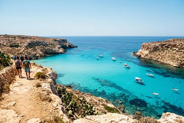 Un viaggio di gruppo WeRoad cammina lungo un sentiero di scogliera rocciosa sopra una baia dal mare turchese costellata di barche