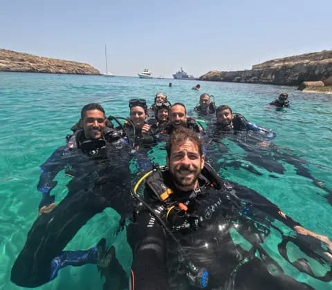 Un gruppo WeRoad in viaggio si scatta un selfie, completamente equipaggiato da sub, mentre galleggia insieme in acque limpide e turchesi.