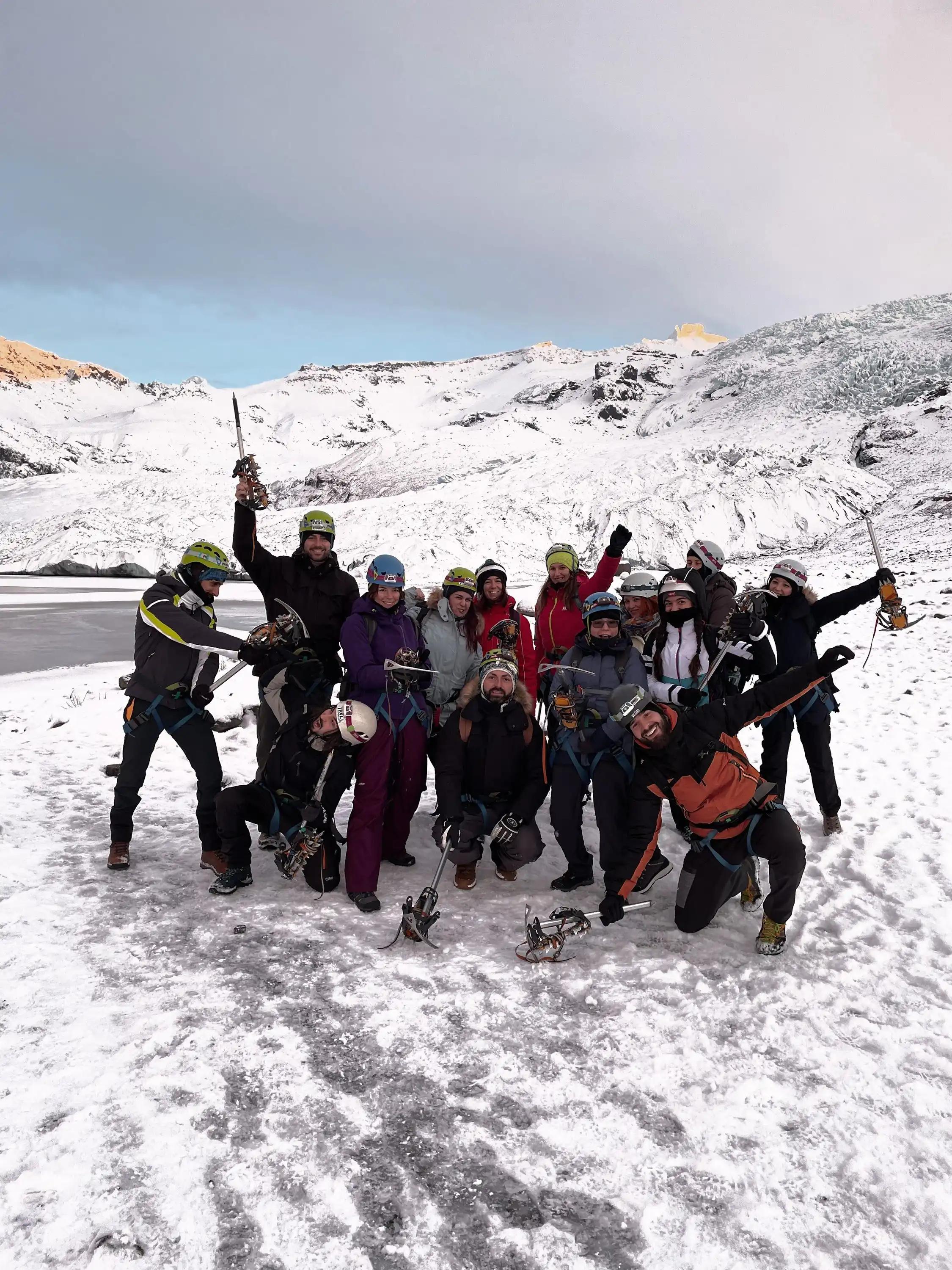 Un viaggio di gruppo WeRoad con caschi e piccozze posa per una foto su un ghiacciaio innevato.