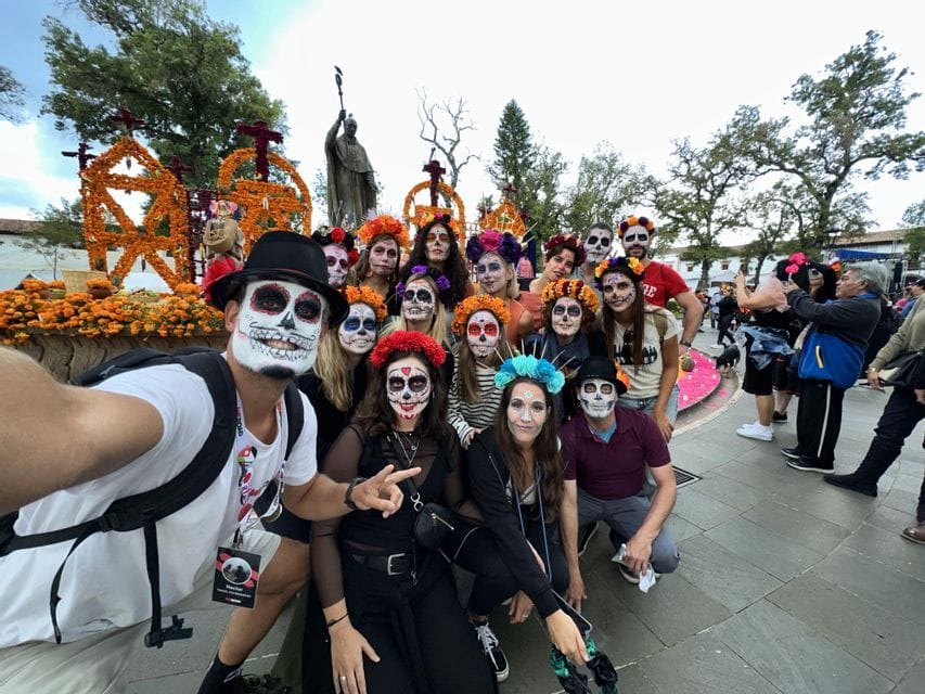 Un gruppo WeRoad si scatta un selfie con i volti dipinti come teschi calavera in una piazza durante un festival.