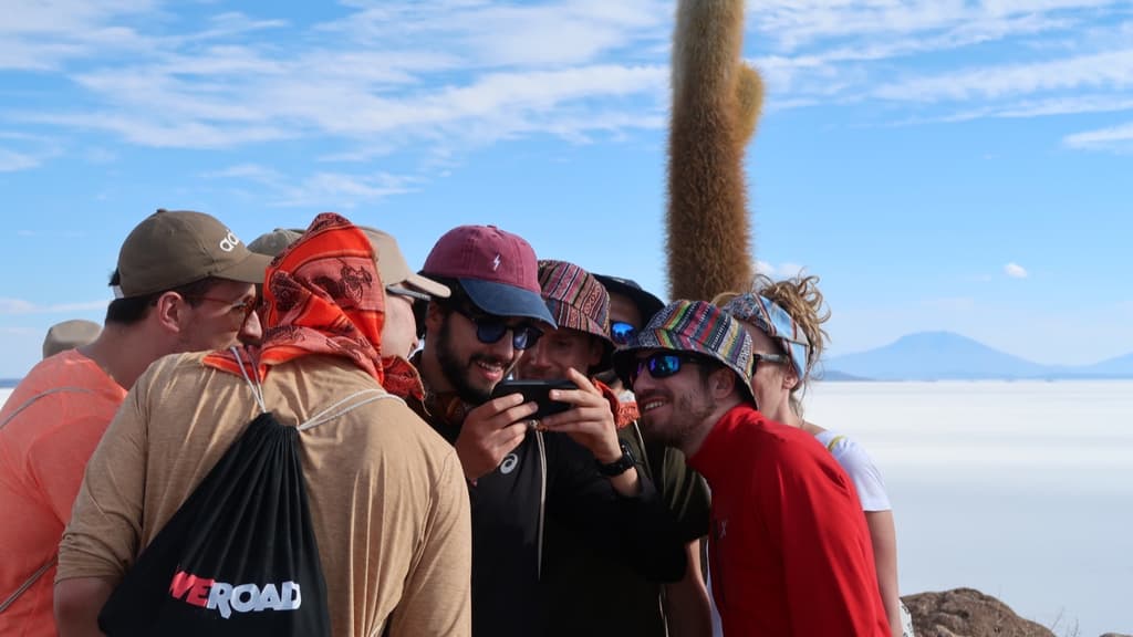 A group huddled around a phone on the Uyuni salt flat