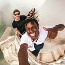 Selfie di un gruppo WeRoad: tre viaggiatori in cima a una struttura curva di arenaria fanno il pollice in su.