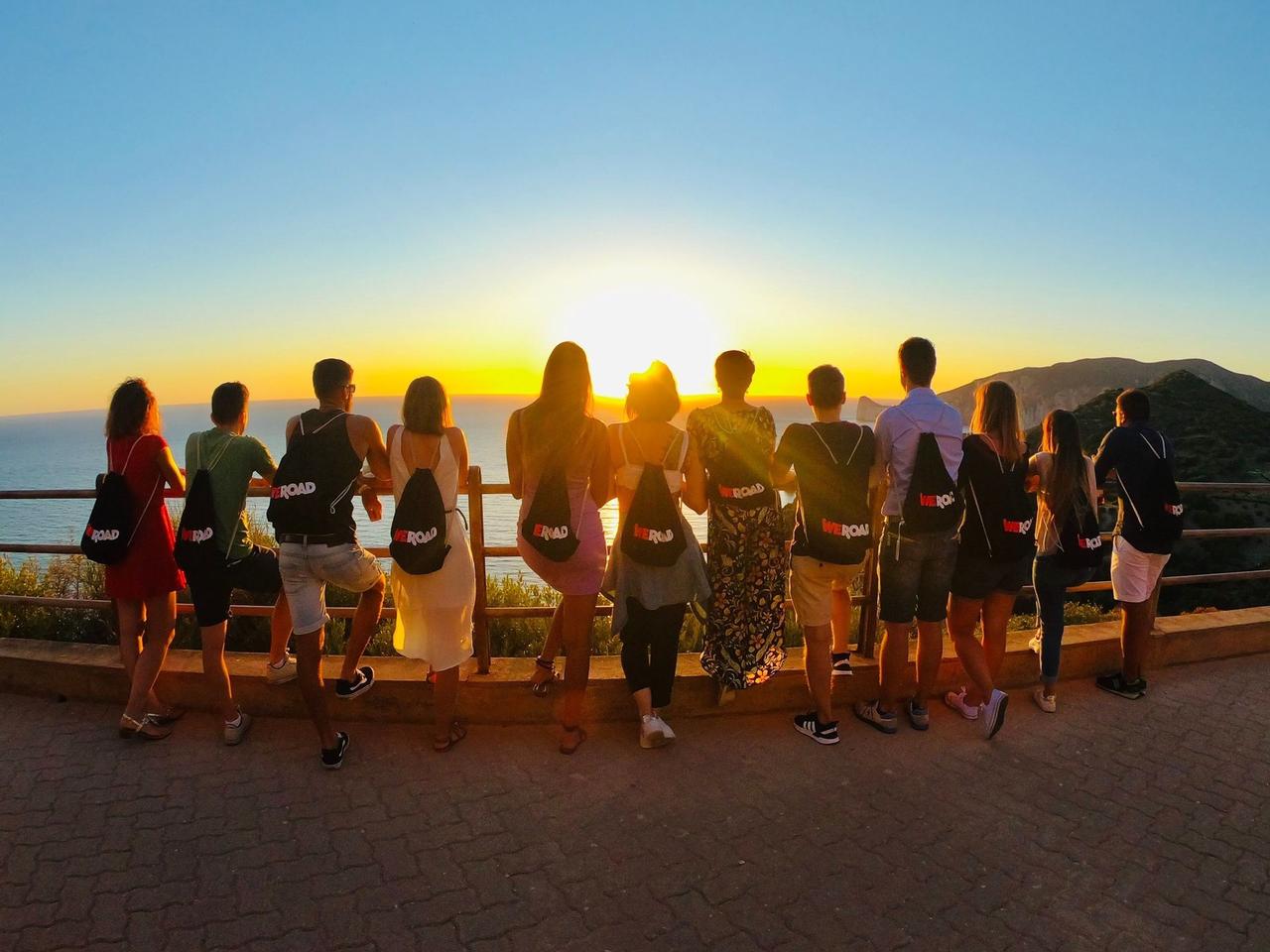 Foto di gruppo al tramonto nel sud della Sardegna con sacchette di WeRoad Vuoi scoprire tutti i nuovi viaggi di WeRoad? I nostri Travel Designer sono sempre al lavoro per ideare nuovi itinerari in tutto il mondo!