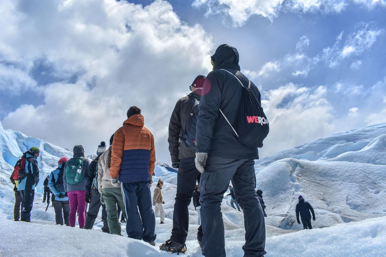 Un voyage de groupe WeRoad en randonnée en file indienne sur un vaste glacier enneigé sous un ciel nuageux.