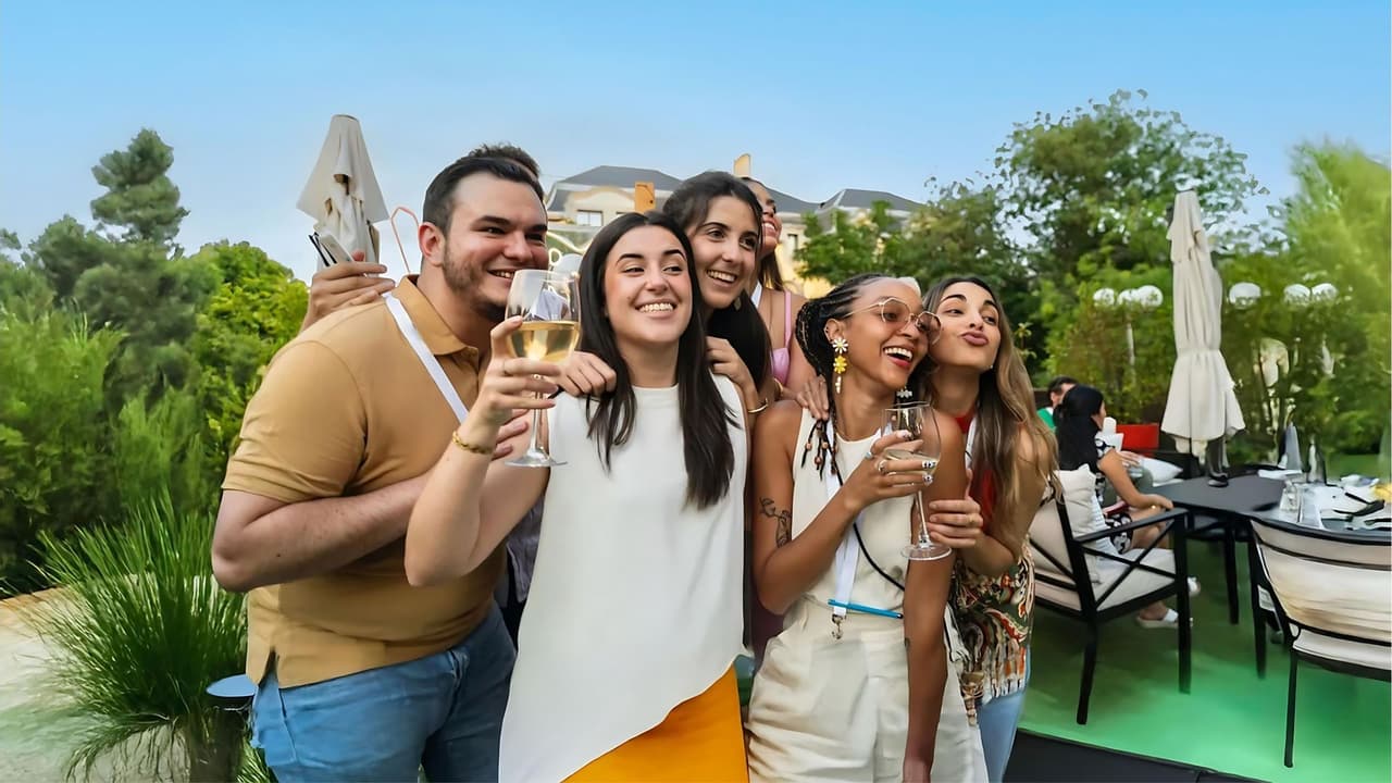 Un grupo de amigos de WeRoad sonriendo y brindando con copas de vino en una terraza al atardecer.