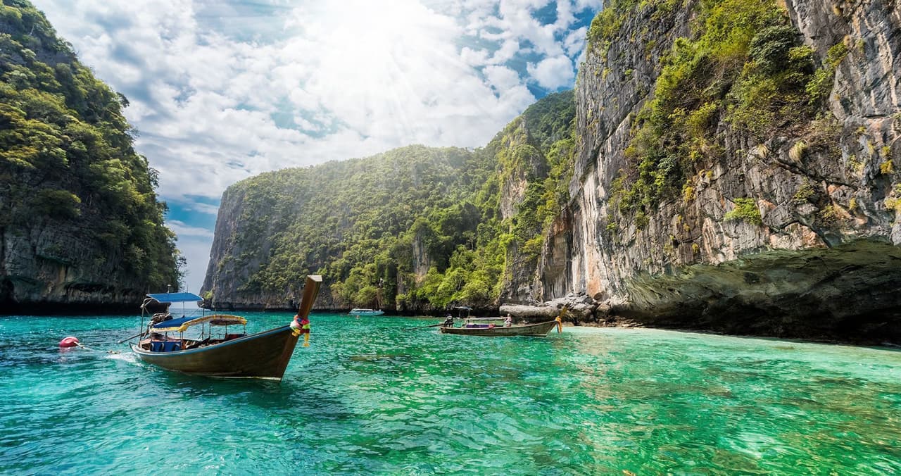 Hai sempre sognato di fare un viaggio in Thailandia? Fatti un WeRoad! Puoi scegliere tra tre itinerari con mood differenti per trovare il viaggio perfetto per te. Barche sul mare in una baia thailandese - WeRoad